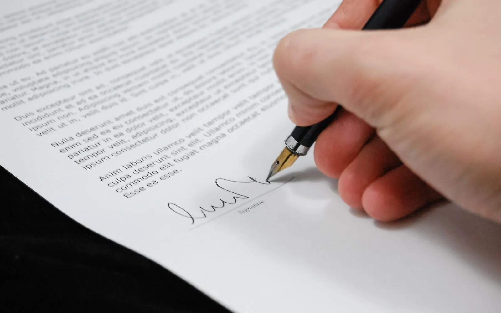 Mão assinando um contrato com caneta-tinteiro